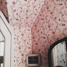 a bathroom with floral wallpaper and a small mirror on the counter next to it