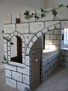 a castle made out of cardboard with ivy growing on the walls and door to another room