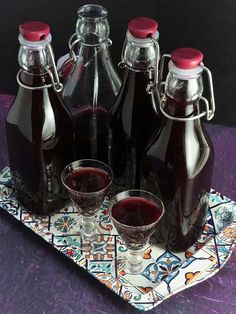 homemade blackberry brandy in glass bottles and glasses on a tray with the words homemade blackberry brandy