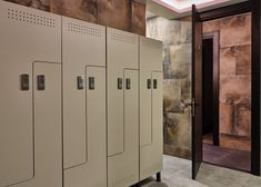 a row of lockers in a room with stone walls and doors on each side