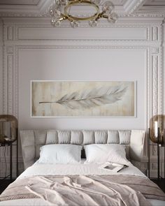 a white bed sitting under a chandelier next to a painting on the wall