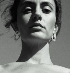 a black and white photo of a woman wearing earrings