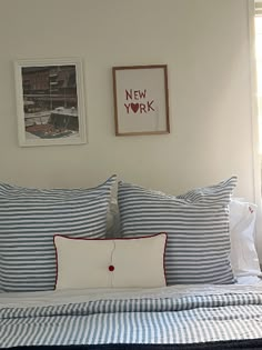 a bed with blue and white striped sheets in a bedroom next to two pictures on the wall