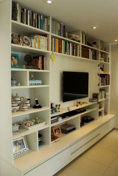 a living room with bookshelves and a flat screen tv mounted on the wall