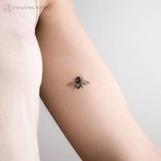 a woman's arm with a small tattoo of a bee on the back of it