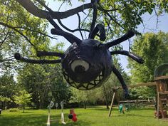 a large spider sculpture hanging from the side of a tree