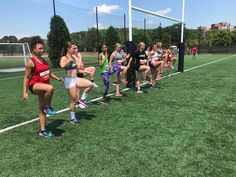 a group of young women standing on top of a soccer field next to each other