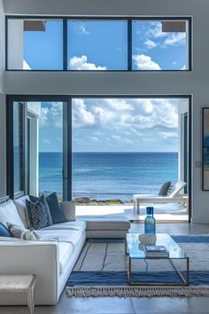 a living room filled with furniture and large windows overlooking the ocean on a sunny day