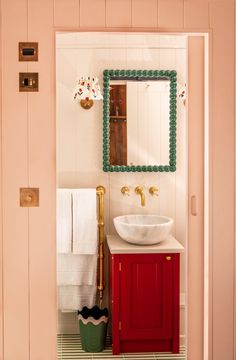 a bathroom sink sitting under a mirror next to a wooden cabinet and wall mounted faucet