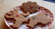 three gingerbread cookies on a white and red plate