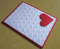 a close up of a greeting card with a heart on the front and an embossed background