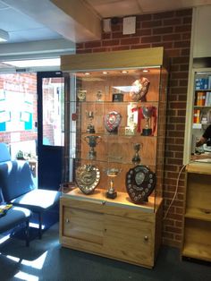 a living room filled with furniture and lots of clocks on glass cases in front of a brick wall