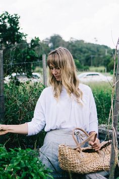 a woman sitting on a bench holding a basket