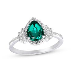 a ring with an emerald colored stone and white diamonds on the sides, set in 18k white gold