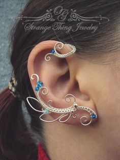 a woman wearing ear piercings with blue stones on it's sides and an intricate design