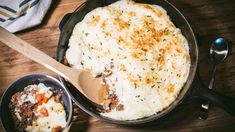 a casserole with meat and cheese in a pan next to a wooden spoon