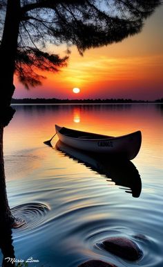 a canoe is sitting on the water at sunset