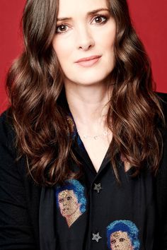 a woman with long brown hair wearing a black shirt and stars on her lapel