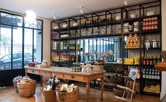 a store filled with lots of different types of food and drink on wooden shelves next to large windows