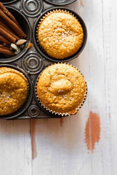 three muffins in a cupcake tin with cinnamon sticks