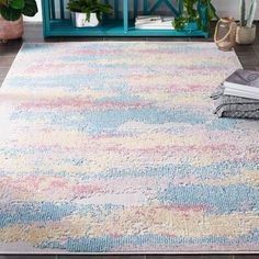 an area rug with multicolored stripes on the floor in front of a blue cabinet and potted plant