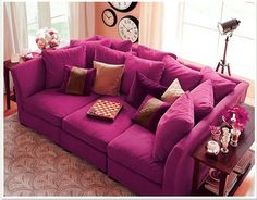 a large red couch sitting on top of a living room floor next to a window