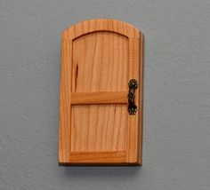 a wooden door is mounted to the side of a gray wall with a black handle