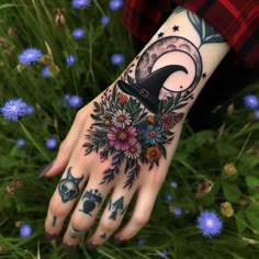 a woman's hand with flowers and a witch hat tattoo on her left wrist