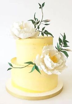 there is a yellow cake with white flowers on the top and green leaves on the bottom