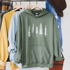 Pine Trees Nature Lover Hiking Camping Hooded Sweatshirt Looking for additional outdoor apparel? Check these out: https://www.etsy.com/shop/TheGraphicPeach?ref=seller-platform-mcnav§ion_id=31675954 Our shop uses direct-to-garment printing to make our products. The design ink is sprayed on, then allowed to soak into the fibers of the garment. This process yields fine quality prints and a smooth finish on the garment. GILDAN UNISEX HOODED SWEATSHIRT With a large front pouch pocket and drawstrings Camping Hoodie, Tree Sweater, Winter Hoodie, Adventure Outfit, Tree Shirt, Evergreen Trees, Winter Hoodies, Pine Tree, Outdoor Apparel