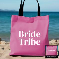 a pink tote bag with the words bride tribe on it sitting in the sand