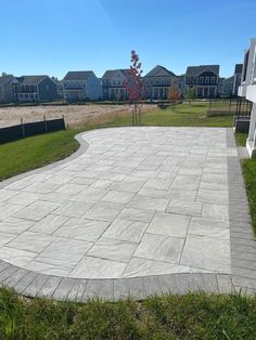 an empty concrete patio surrounded by grass and houses in the backround with blue sky