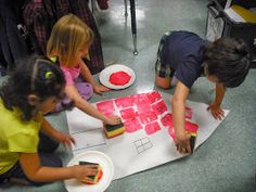 three children are painting on paper plates with red watercolors while another child is holding a paintbrush