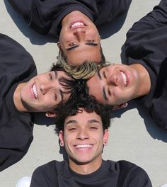 four people are standing in a circle looking up at the camera with smiles on their faces