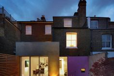 a modern house with an outdoor dining area and patio in the evening time, lit up at night