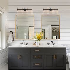 a bathroom with double sinks and two mirrors on the wall next to a bathtub