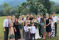 a group of people standing next to each other in front of a lush green field