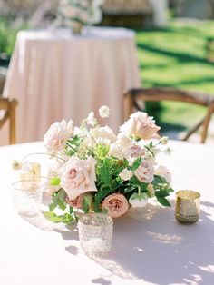 a table with flowers and candles on it in front of an outdoor dining set up