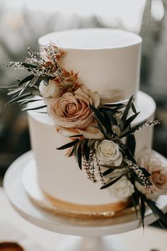 a wedding cake decorated with flowers and greenery