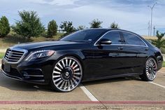 a black mercedes s - class parked in a parking lot with chrome rims and wheels