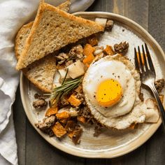 an egg is on top of toast with mushrooms and other foods in the plate next to it