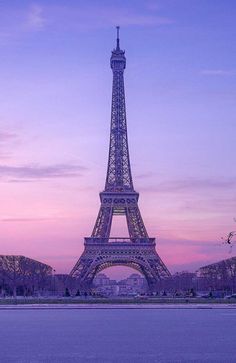 the eiffel tower is lit up at dusk