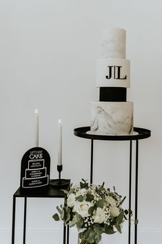 a white and black cake sitting on top of a table next to a vase with flowers