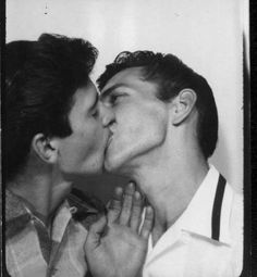 two men are kissing each other in an old black and white photo, with one holding his face to the other's chest