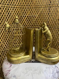 two brass figurines are sitting next to each other in front of a rat cage