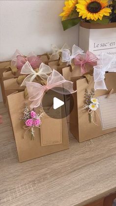 several small bags with bows on them sitting on a table next to sunflowers