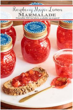 several jars of jelly sit on a plate with bread and jam in the foreground