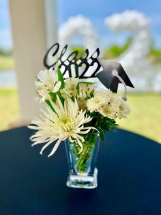 a vase filled with white flowers sitting on top of a table next to a sign