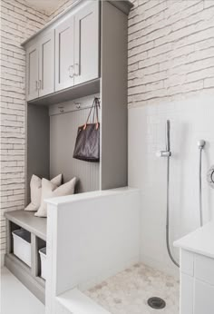 a white bathroom with a bench, shower head and cabinets in the back ground area