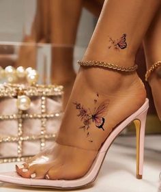 a woman's foot with butterfly tattoos on her left ankle and gold chain around the ankles